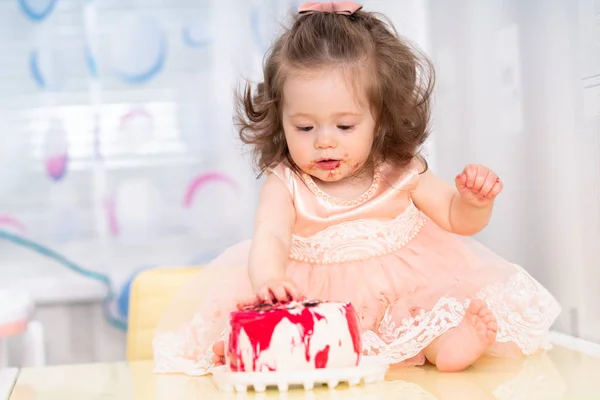 Rommelig meisje eten van een cake van de kindverjaardag — Stockfoto
