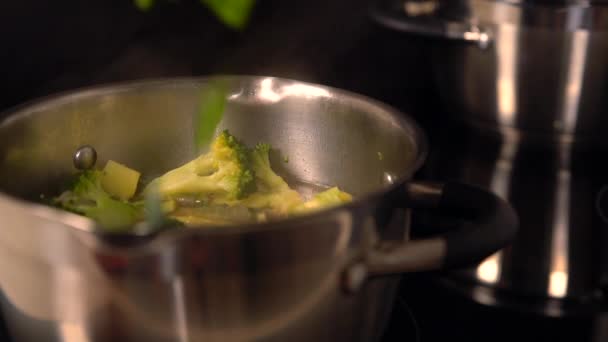 Verduras de hoja que se añaden a una olla de brócoli — Vídeo de stock