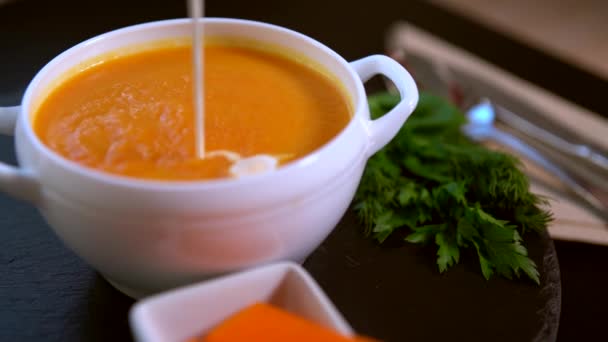 Chef añadiendo crema de guarnición a sopa de calabaza — Vídeo de stock