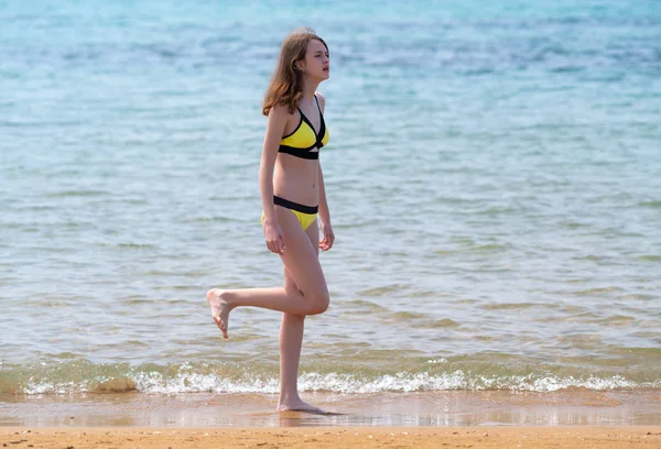 Young woman in a bikini balancing on one leg — Stock Photo, Image