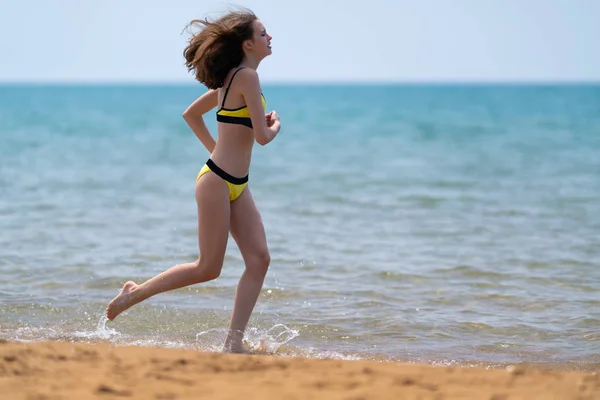 Стройная молодая женщина бегает по пляжу — стоковое фото