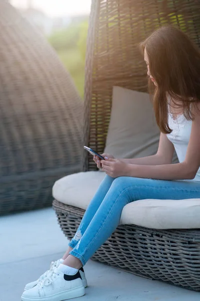 Jeune femme décontractée en jeans assise dans une chaise — Photo