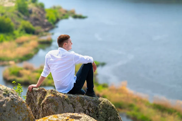 Young man sitting on an elevated rock — 스톡 사진