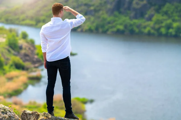 Man standing on a hilltop looking out over a river — Stock Photo, Image