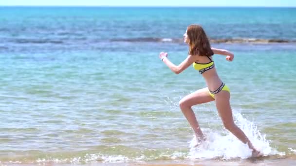 Mujer joven en bikini corriendo por el mar — Vídeo de stock