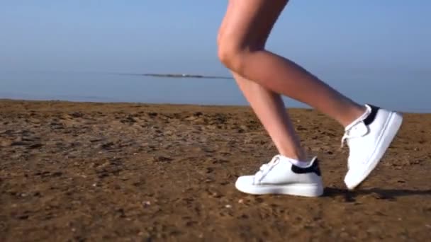 Genç bir kadın ya da kız denizin kenarındaki kumsalda gün batımında koşuyor.. — Stok video