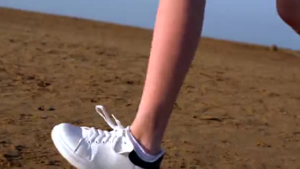 Pies y zapatillas de deporte de una mujer joven en una playa — Vídeos de Stock