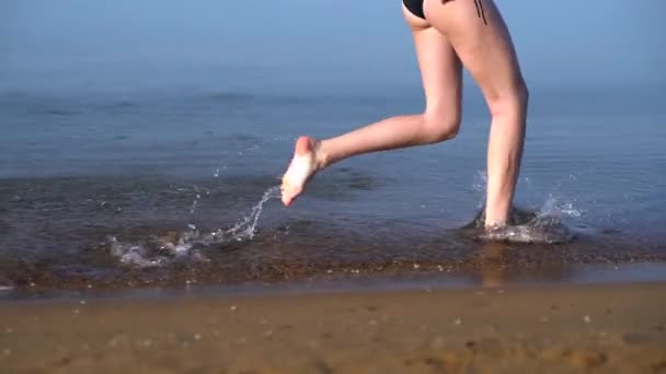 Mujer joven en bikini corriendo en el mar — Vídeo de stock