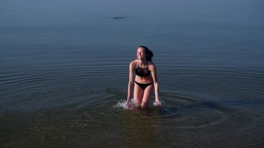 Okyanusta oynayan gülümseyen mutlu genç kadın