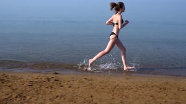 Fit genç kadın gün batımında bir plajda koşu