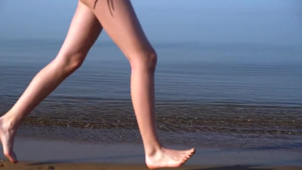 Mujer joven corriendo a lo largo de una playa de arena — Vídeos de Stock