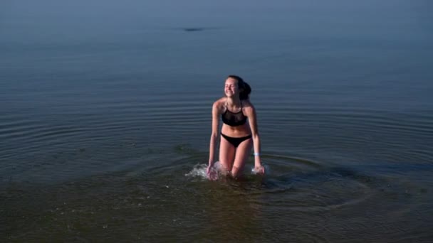 Souriant jeune femme heureuse jouant dans l'océan — Video