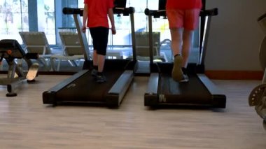 Koşu bandında egzersiz yapıyor iki kişi