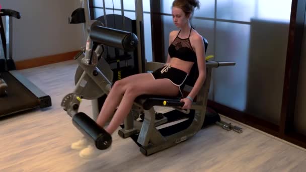 Fittes junges Mädchen mit einem Bauchtrainer in einem Fitnessstudio — Stockvideo