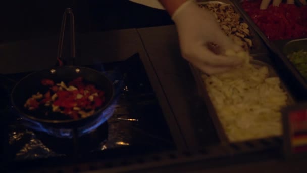 Gehandschoende hand van een kok die ingrediënten toevoegt aan een pan — Stockvideo