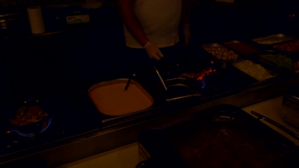 Chef retournant poêle à frire flamboyante dans la cuisine sombre 