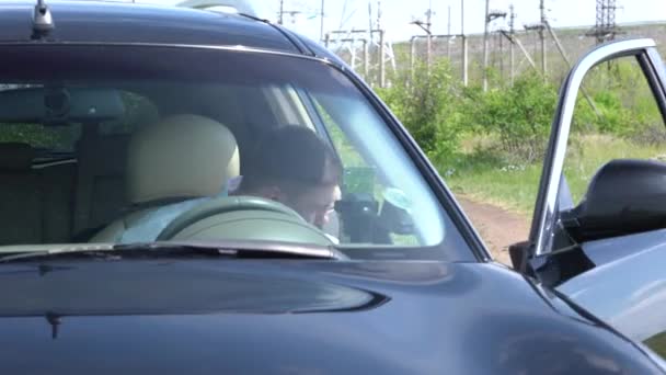 Young man exiting a parked car in the countryside — Stock Video