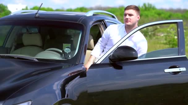 Молодой человек выходит из припаркованной машины — стоковое видео