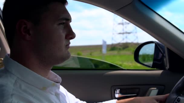 Молодой человек в белой рубашке за рулем автомобиля — стоковое видео