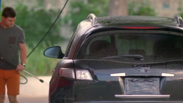 Mladý muž čistí své auto vysokotlakou pěnou — Stock video