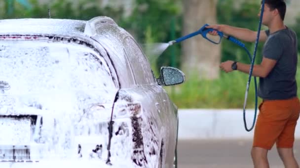Jovem mangueira para baixo seu carro coberto de sabão suds — Vídeo de Stock