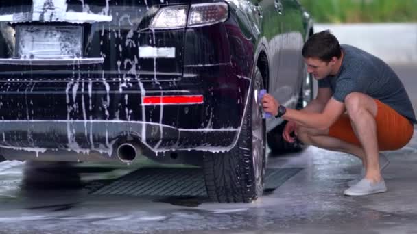 Joven limpiando su coche negro — Vídeo de stock