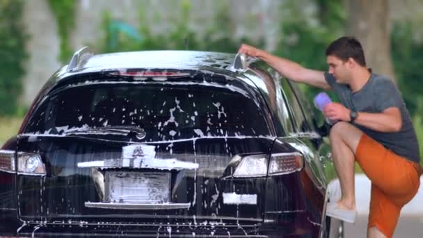 Junger Mann klettert auf das Steuer seines Autos — Stockvideo