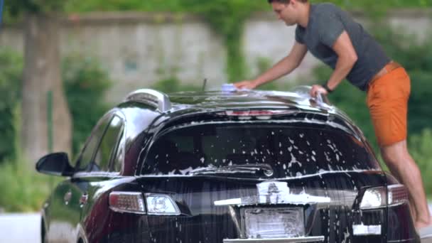 Young man washing the roof of his car — Stock Video