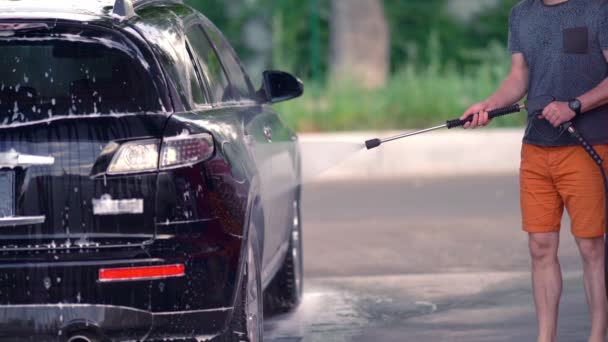 Ung mand spuler shampooen af sin bil – Stock-video