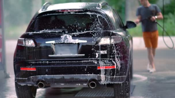 Jeune homme laver sa voiture à un lavage de voiture manuel — Video