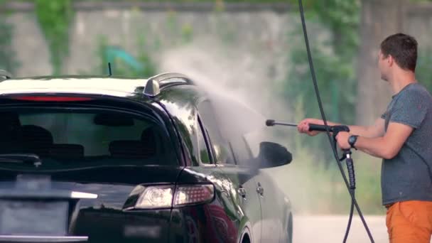 Jovem pulverização de seu carro com água limpa — Vídeo de Stock