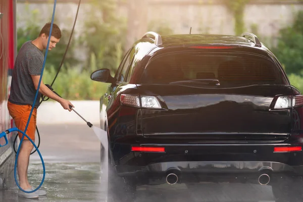Чоловік миє машину за допомогою системи високого тиску — стокове фото