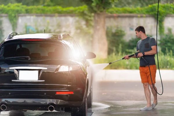 Ung man som slangar tvål suger av sin bil — Stockfoto