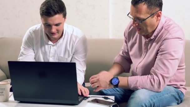 Πατέρας και γιος εργάζονται σε ένα φορητό υπολογιστή μαζί — Αρχείο Βίντεο