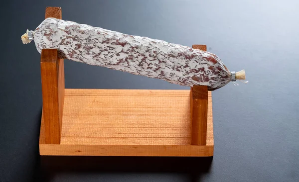 Whole spicy cured Italian salami on a wood stand — Stock Photo, Image