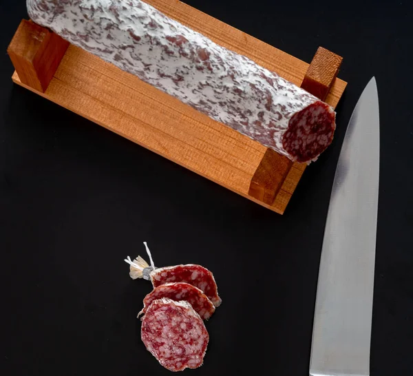 Coltello da chef grande accanto a un salame su uno stand — Foto Stock