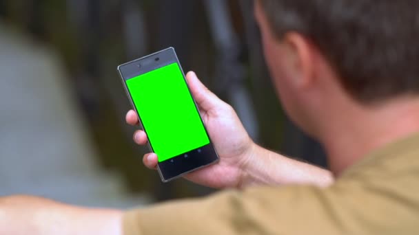 Homme relaxant en plein air lisant sur un smartphone 