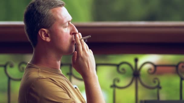 Чоловік насолоджується цигаркою на відкритому повітрі в парку — стокове відео