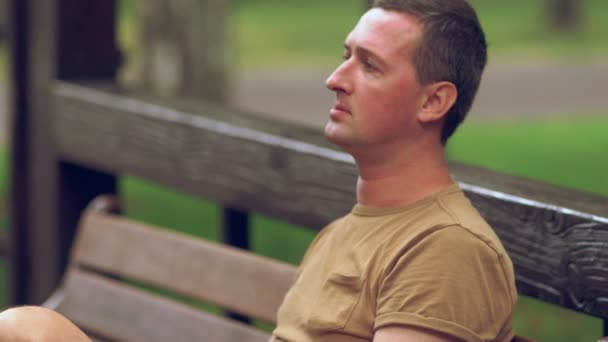 Hombre disfrutando de un humo al aire libre en un banco — Vídeos de Stock