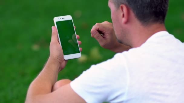 Unrasierter Mann im T-Shirt surft auf Handy — Stockvideo