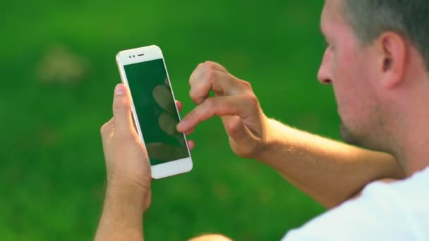 Небритый мужчина средних лет, прокручивающийся по мобильному телефону — стоковое видео
