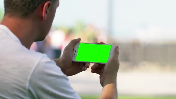 Hombre sosteniendo un teléfono móvil en blanco en un evento — Vídeos de Stock