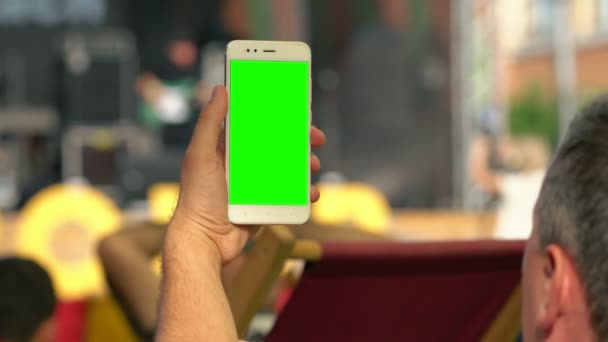 Hombre sosteniendo un móvil en blanco en un evento — Vídeo de stock