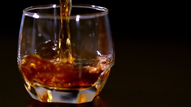 Versare il brandy o il whisky in un bicchiere con ghiaccio — Video Stock