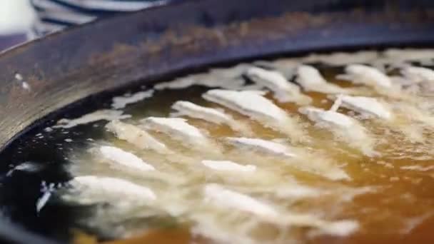 Рука шеф-повара в перчатках помещает рыбу в горячее масло — стоковое видео