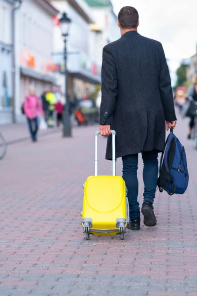 Человек уходит, вытаскивая желтый чемодан — стоковое фото