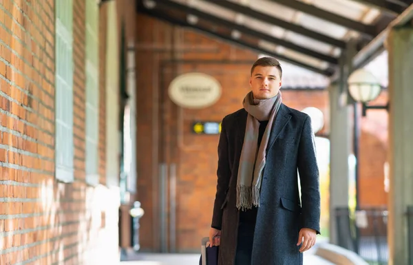 Young man in overcoat and scarf approaching — Stock Photo, Image