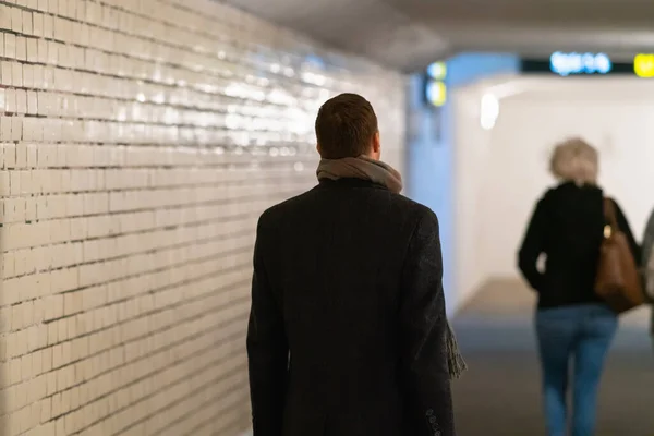 Man in overcoat following a woman in subway — Stock Photo, Image