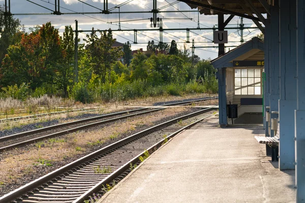 Pusty peron z liniami kolejowymi i stacją — Zdjęcie stockowe