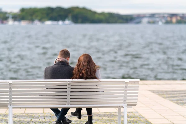 Пара сидящих на скамейке с видом на воду — стоковое фото